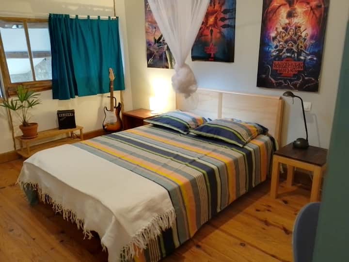 卧室包括一张双人床、书桌、架子，紧邻马桶和大浴室。 