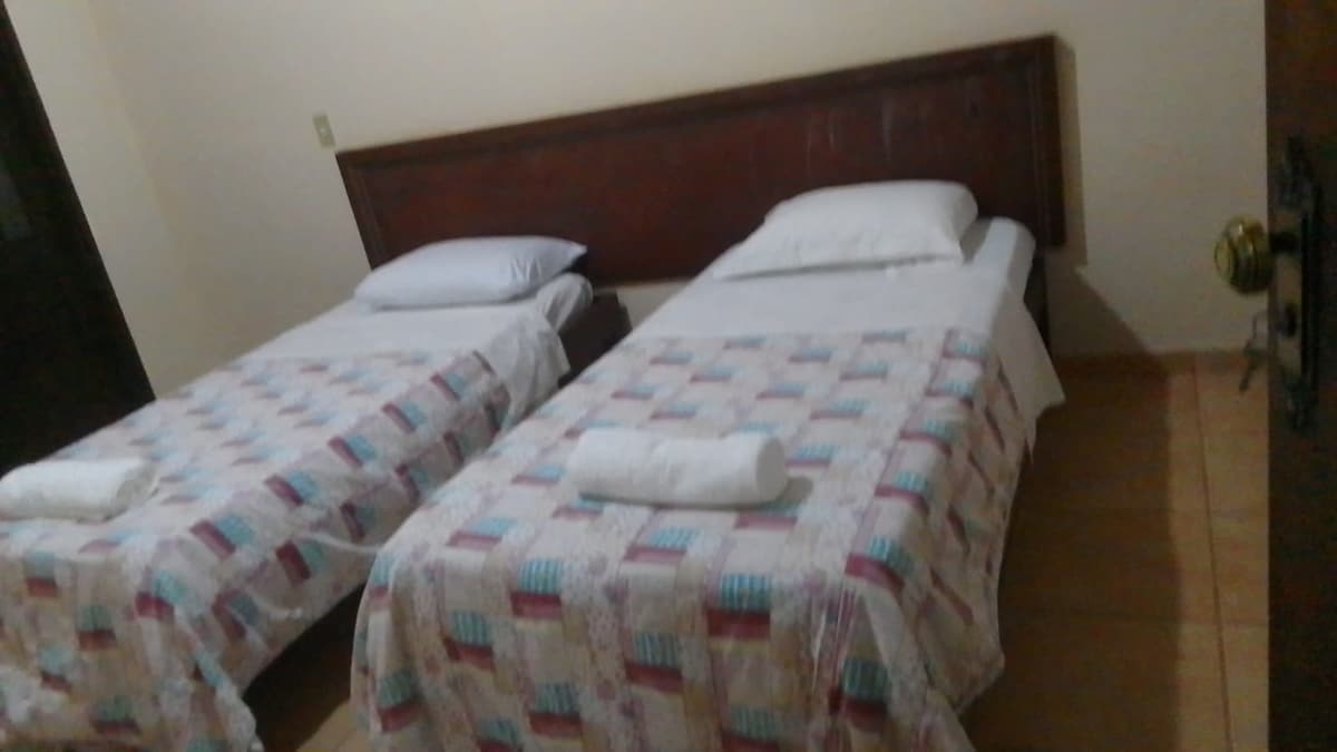 Quarto com sacada equipadp com dois módulos que podem ser configurados como duas camas de solteiro ou uma cama tamanho king.  Ventilador de teto. Conta com amplo salão e banheiro social compartilhado com apenas outro quarto.