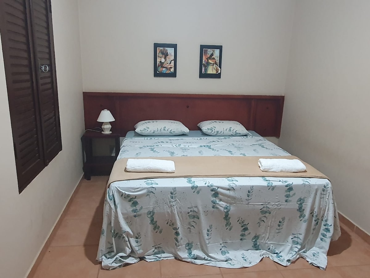 Quarto com cama tamanho king composta por dois módulos que, se separados formam duas camas de solteiro.  É possível acrescentar um colchão avulso. Ventilador de teto. Banheiro privativo.