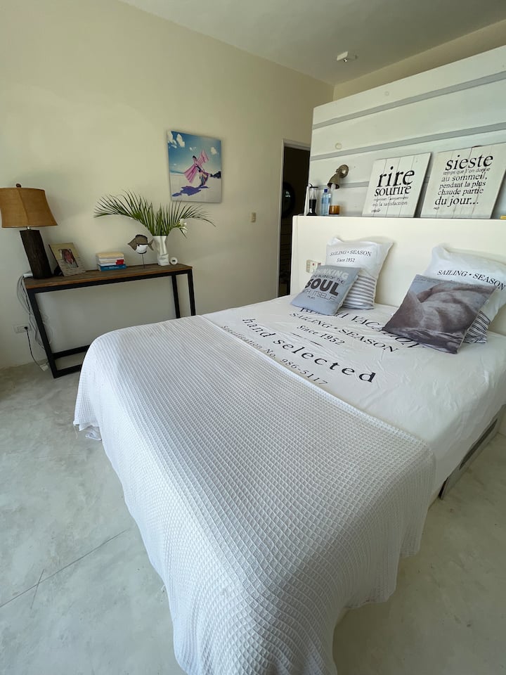 Hoofdslaapkamer  1 met uitzicht op het eigen terras, met uitzicht op natuur en zee. Queensize bed met kleedkamer, badkamer en en-suite toilet.  De plafondventilator en de zijluik openen naar de natuur, garanderen permanente ventilatie.