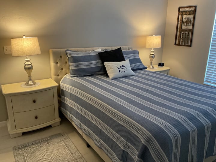 Suite de invitados con cama tamaño queen, sábanas de satén, TV montadas en la pared, ventilador de techo.