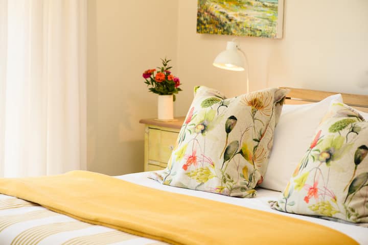 Main bedroom downstairs - its a comfy queen bed with lovely linen and fluffy towels.  It has a small private patio through the sliding door of the room for your morning coffee and to check the waves.