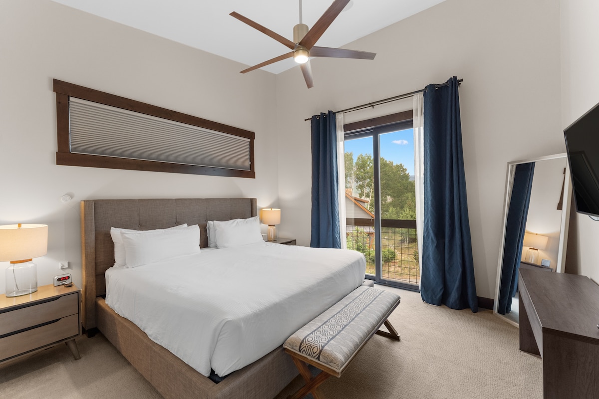 Главната спална соба на главното ниво вклучува брачен кревет, монтиран телевизор, поглед кон планината и сопствена бања. 