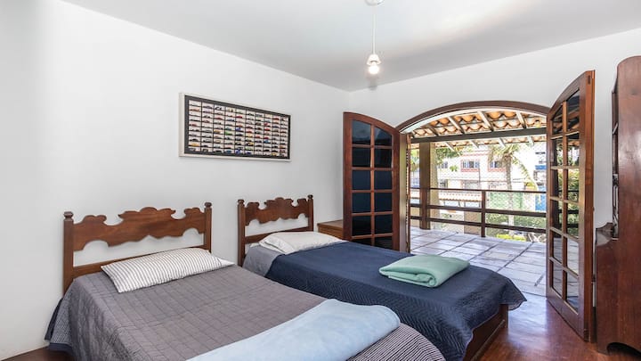 Vista del tercer dormitorio con dos camas individuales y salida al balcón superior con vistas a la piscina y a los jardines de la casa. El dormitorio de Eset tiene un televisor inteligente de 42pulgadas, aire acondicionado y armarios empotrados.