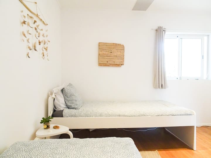 Oliveira Suite's Twin bedroom, with beachy decorative features and individual storage spaces for clothes and belongings.