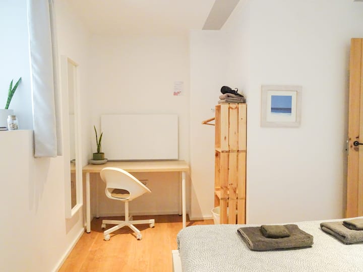 Oliveira Suite's Master bedroom, featuring an en-suite bathroom, dedicated workspace, and storage space for clothes.