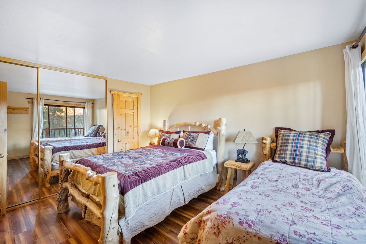 This bedroom features stunning Aspen Lodge bed frames with a queen and twin bed for flexible sleeping options. A private deck off the room fills the space with natural light, creating a bright and inviting retreat.