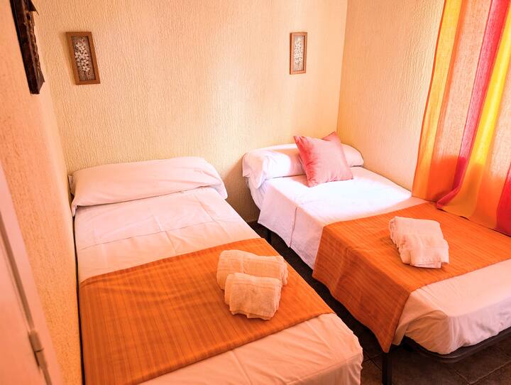 Dormitorio con 2 camas individuales y armario. Una de las camas es nido y se puede recoger debajo de la otra para más espacio.