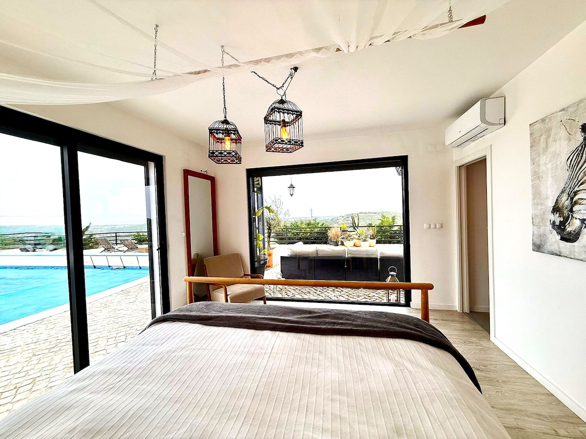 Elegante dormitorio principal con un impresionante ventanal que te permite despertarte con la belleza del amanecer. Luminoso, sereno y espacioso, perfecto para relajarse y comenzar el día con tranquilidad. ¡Sal a la piscina también! 