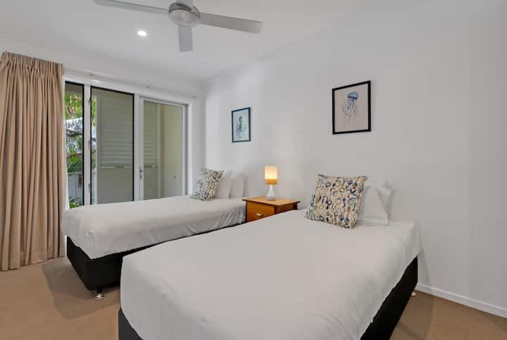 Chumba cha kulala cha tatu kinalala wawili katika vitanda vya mtu mmoja na feni za dari na kiyoyozi ili kuweka joto baridi.