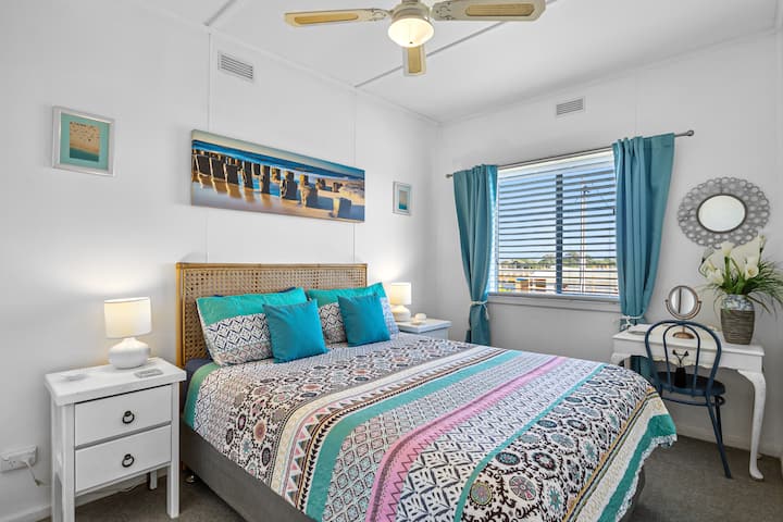 ห้องนอนใหญ่ชั้นบนพร้อมเตียงควีนไซส์และตู้เสื้อผ้าขนาดใหญ่และพัดลมเพดาน 