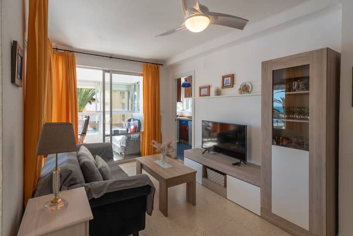 Obývacia izba s pohovkou, televízorom a prístupom na terasu.