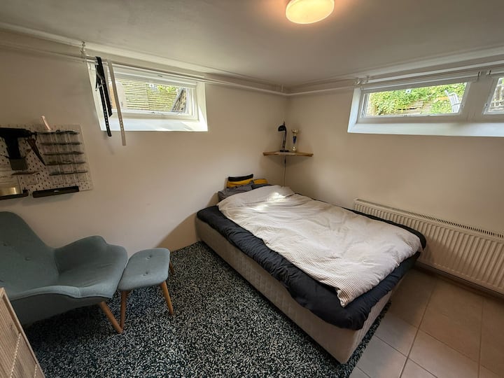 Veľká spálňa v suteréne s manželskou posteľou Queen, veľkou televíziou, zásuvkami a kreslom. 