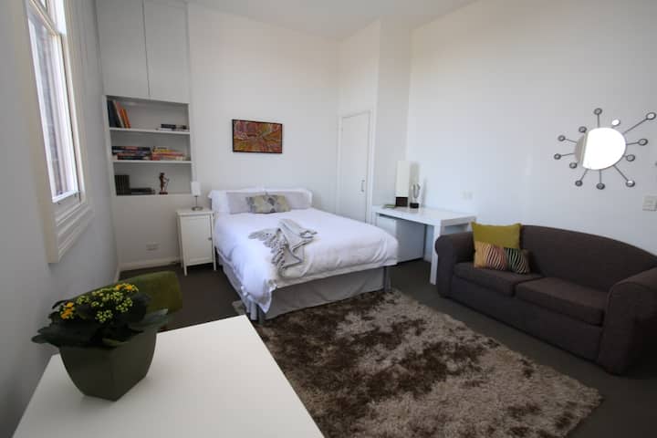 Mesa de comedor, ventana doble con vistas a la ciudad cbd, estantería, armario de noche con lámpara de lectura, cama doble con almacenamiento debajo, armario, escritorio y sofá doble.