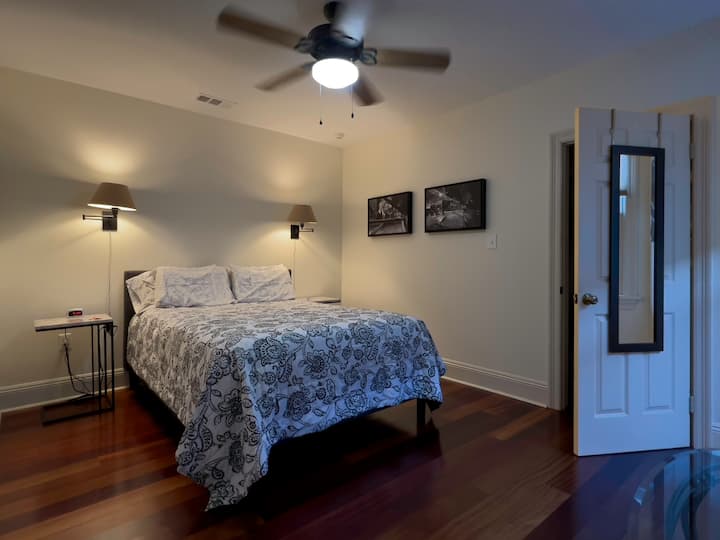 Letto matrimoniale nella camera da letto con cabina armadio dietro la porta con specchio.  Ogni comodino ha alimentazione e prese USB.