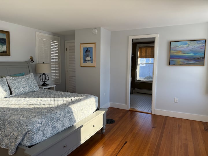 Dormitorio principal luminoso y espacioso con una cómoda cama tamaño queen, pisos de madera noble y abundante luz natural. Incluye un baño privado en la habitación para mayor comodidad y confort: un refugio relajante después de un día de playa.