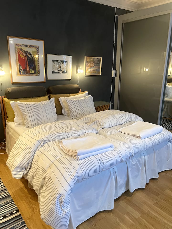 Cama de casal em quarto grande e acesso ao guarda-roupa.