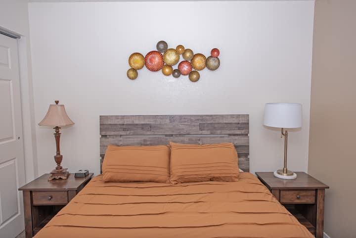 The bedroom features a comfortable queen-sized bed, blackout curtains on the window, nightstands, a dresser and a closet.