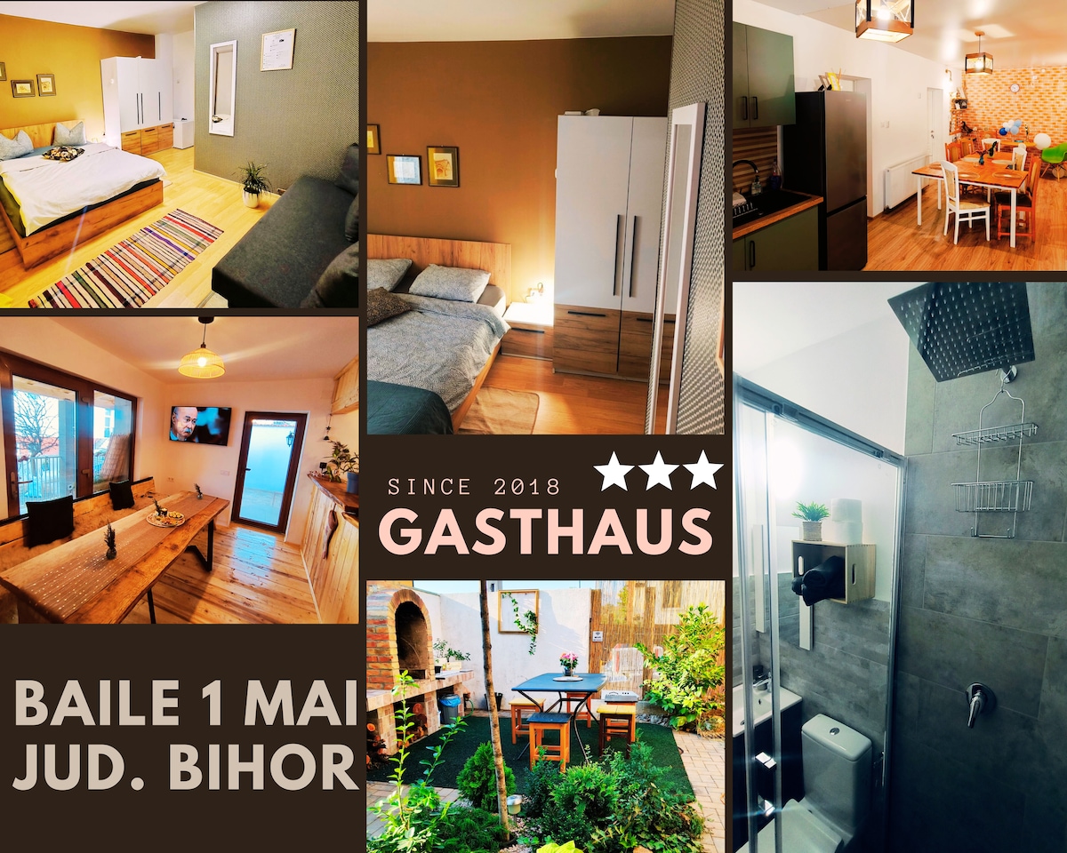 Collage of various spaces within Gasthaus, displaying a cozy bedroom with two beds, a dining area with wooden furniture, and a modern bathroom featuring a walk-in shower. An outdoor seating area is visible, surrounded by greenery, creating a relaxed atmosphere.