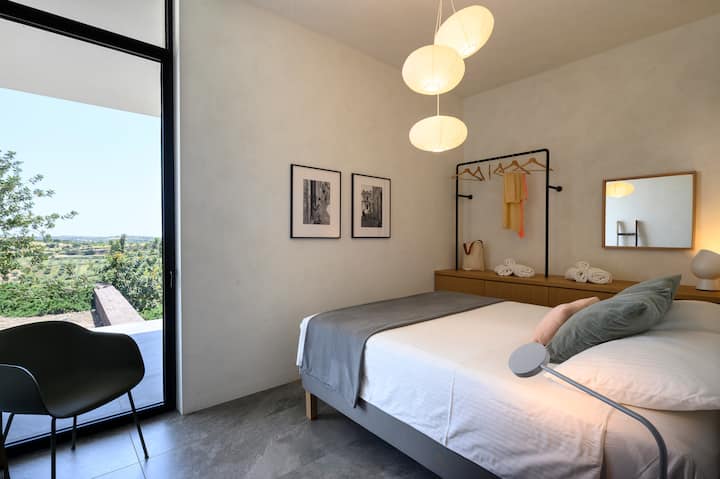 Chumba cha pili cha kulala katika sehemu kuu ya vila kina mlango wa kioo unaoelekea kwenye veranda ya mashariki ulio na mwonekano wa bustani za carob na bahari ya Ionian. 