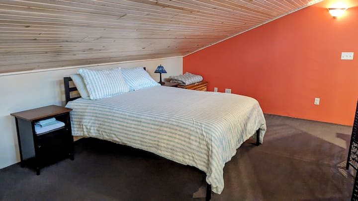 The upstairs loft bedroom has two queen size bed, chair with ottoman and a pair of privacy panels. 