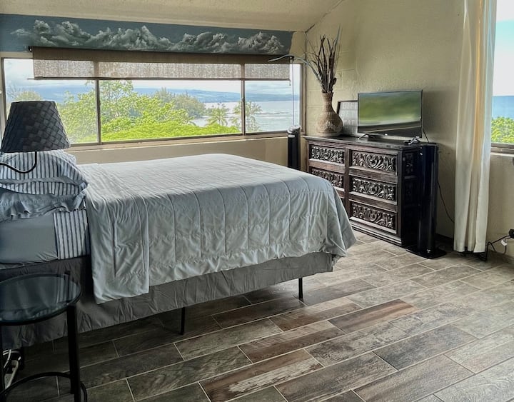 חדר שינה ראשי מרווח עם חלונות פינתיים, עם כמובן, נוף מדהים.  