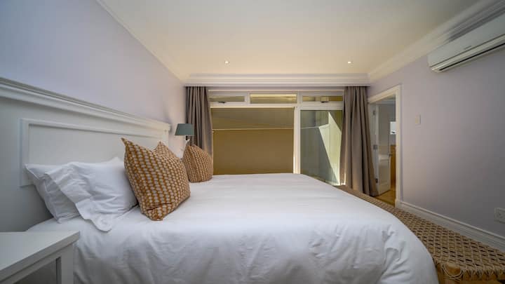 通往侧面露台的加大双人床、带淋浴间、马桶和洗手盆的套房浴室