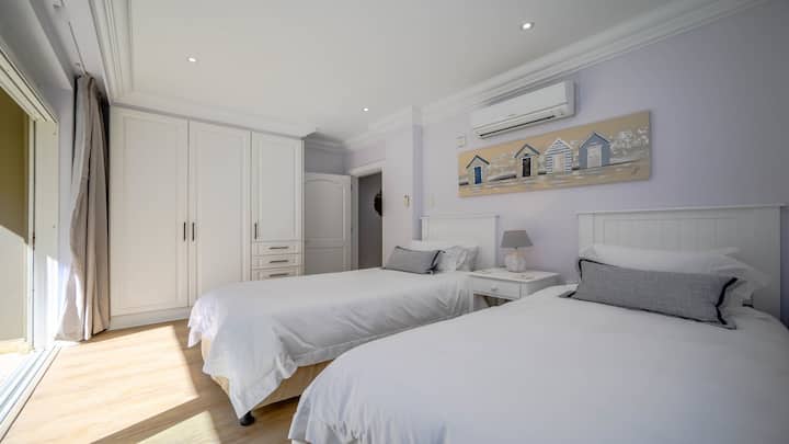 两张单人床通往侧露台，套房卫生间配有浴缸、淋浴间、马桶和洗手盆