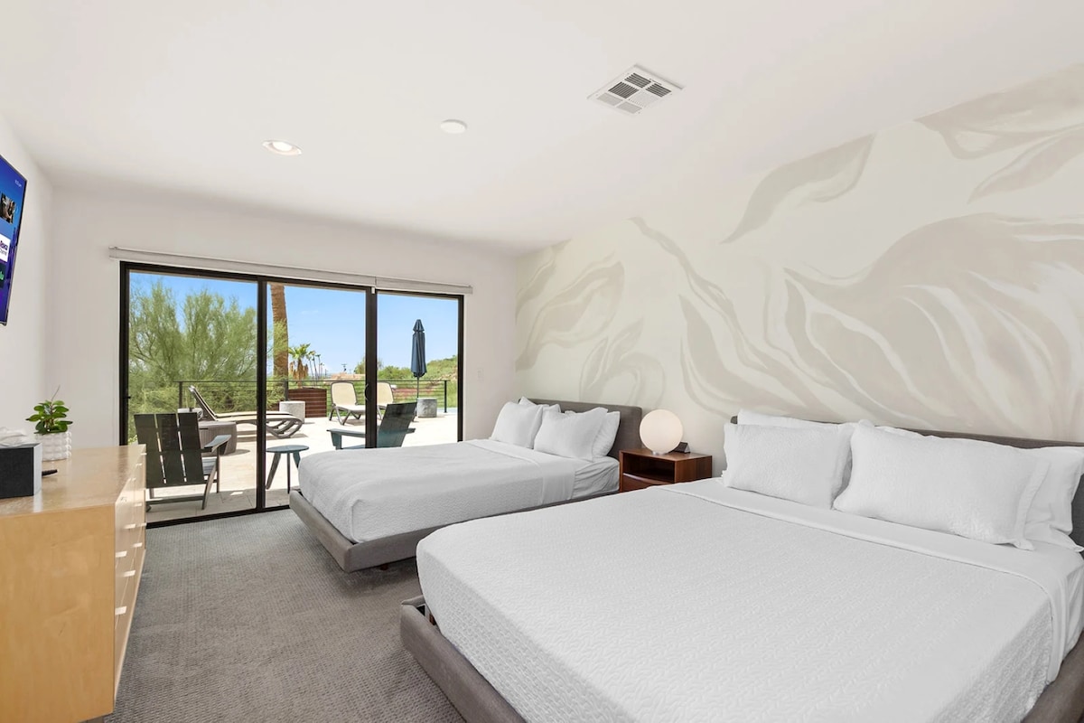 Wake up to sunshine and serenity in this bright, stylish bedroom featuring 2 queen beds, modern art, and direct access to a private patio with stunning desert views.