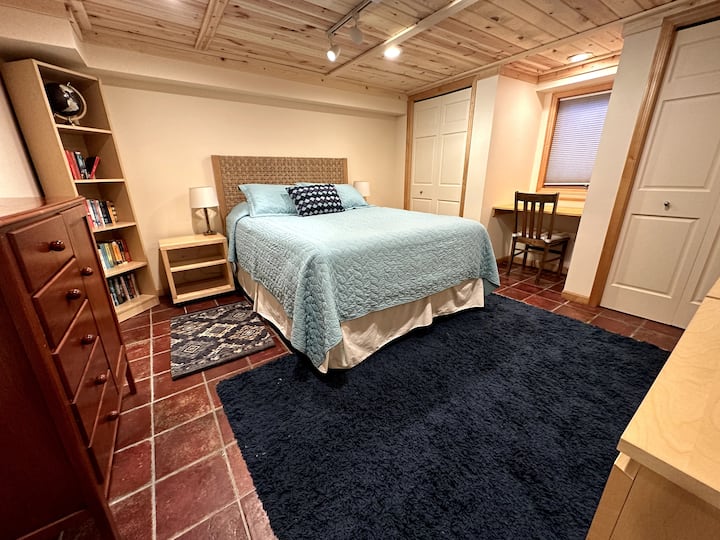 这间卧室位于房子的底层，设有一张舒适的标准双人床、一个专用工作空间，以及充足的衣服和个人物品存放空间。