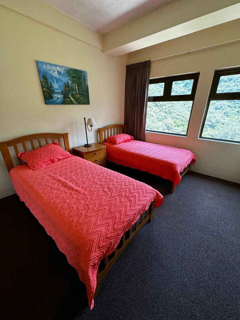 Recamara con 2 camas tamaño imperial, ideal para niños con ventana que tiene vista al parqueo y montañas.