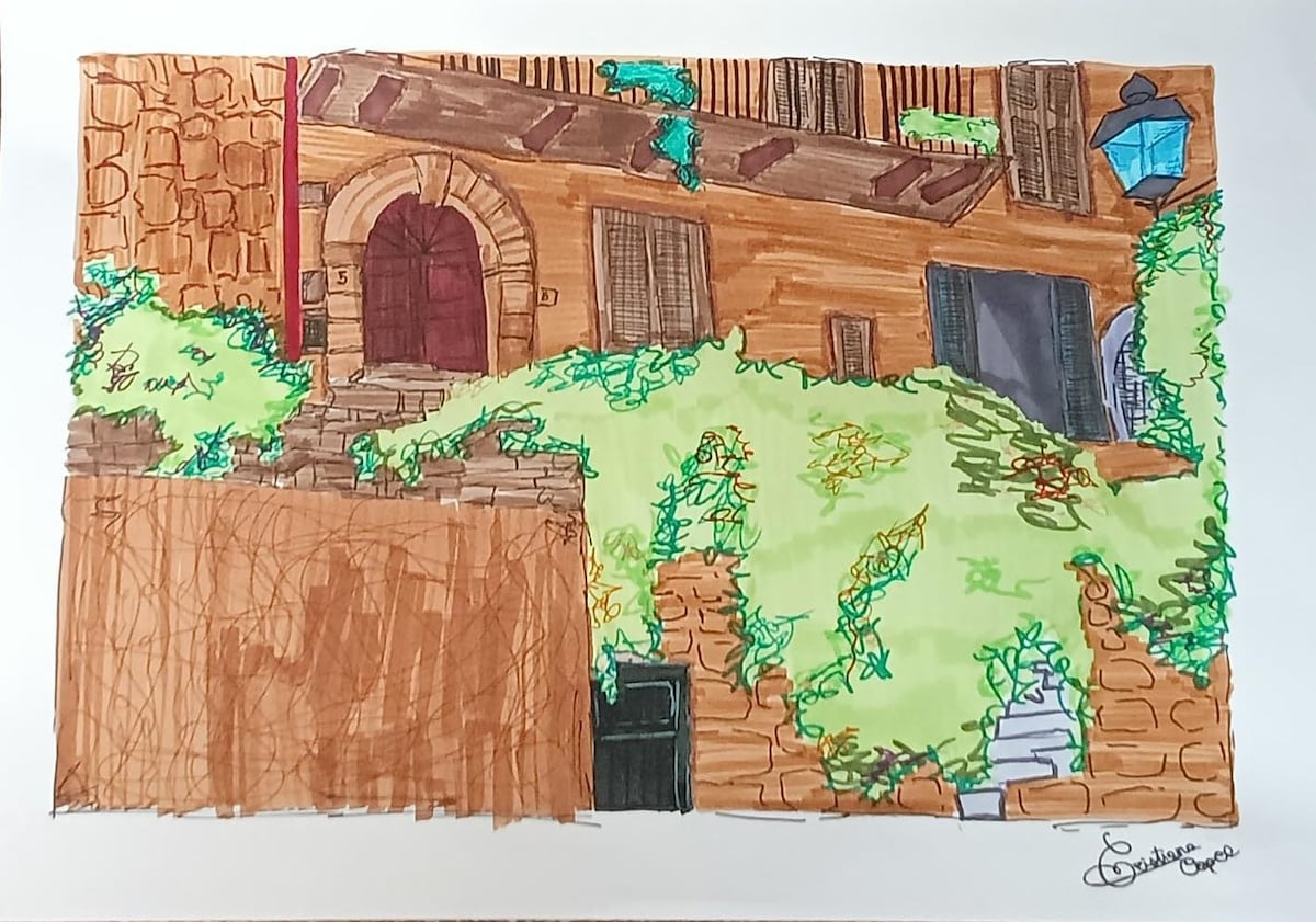 An illustration depicts a charming stone building with a red door and wooden shutters. Lush greenery covers the exterior, enhancing the warm tones of the brick walls. A lamppost stands nearby, adding to the character of the inviting scene.