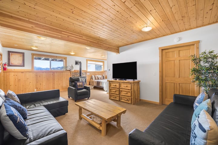 Sebule kubwa ya ghorofa ya chini iliyo na meko ya ndani, runinga na vitanda viwili vya sofa.