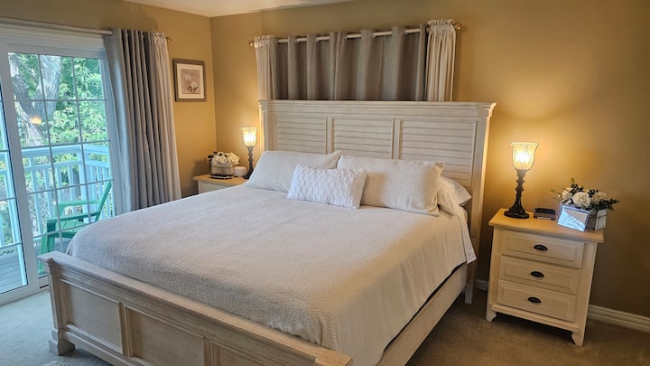 Main bedroom with additional amenities:  ensuite bathroom and shower, private balcony overlooking the Bay, nightstand with drawers, alarm clock with charging base, and Dohm noise machine.