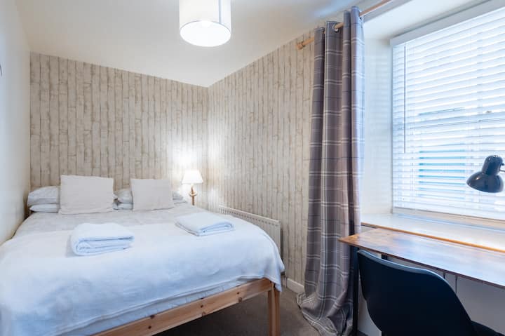 Útulná spálňa s manželskou posteľou a vyhradeným pracovným priestorom. 