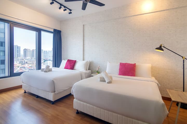 This modern bedroom features the luxurious King Koil beds, ample natural light from large windows showcasing the city and sea.