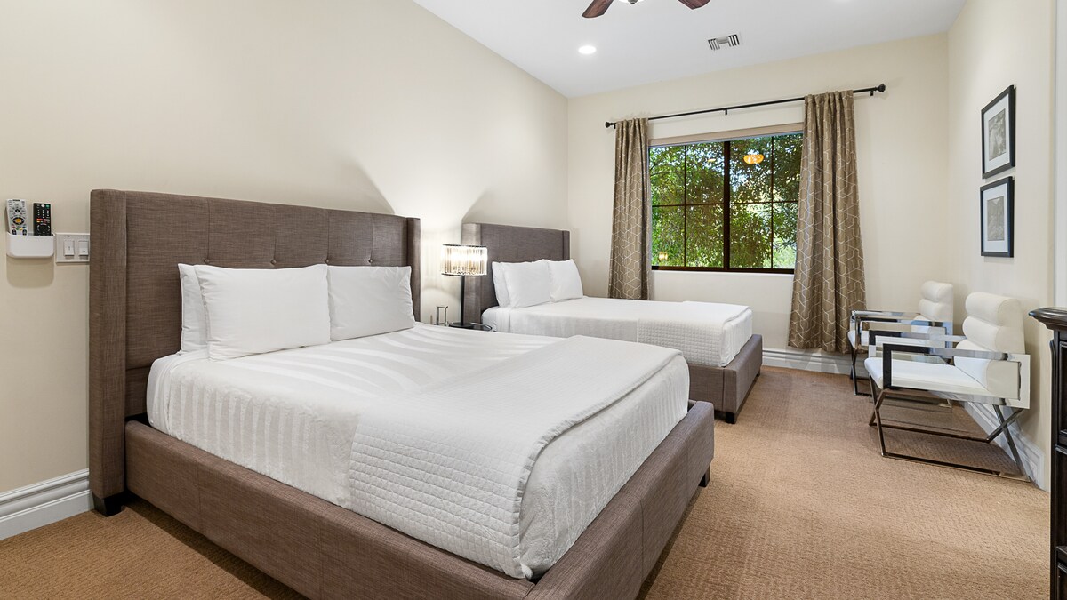 Priestranná spálňa s dvoma luxusnými manželskými posteľami, prirodzeným svetlom a štýlovou výzdobou pre pokojný pobyt