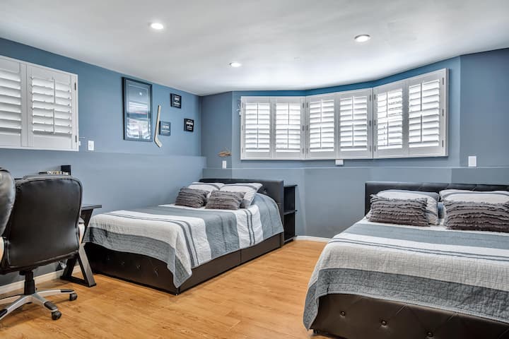 Camera da letto luminosa ed elegante con due letti matrimoniali, bagno privato e due postazioni di lavoro dedicate, ciascuna con la propria sedia ergonomica. Rilassati nel lusso su un materasso ipoallergenico ibrido: il comfort ridefinito!