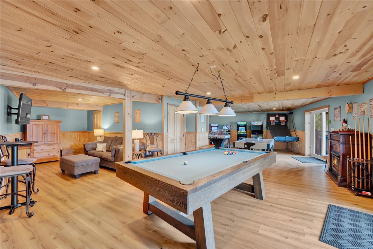 Herná miestnosť v suteréne: priestor na sedenie s rozkladacou pohovkou, televízor, biliardový stôl, stôl na vzdušný hokej, bublinový hokej, mini basketbalová hra, pinball Star Wars, hra Outrun Driving, hra Multi Arcade, obrovské piškvorky, stolové hry a krb.