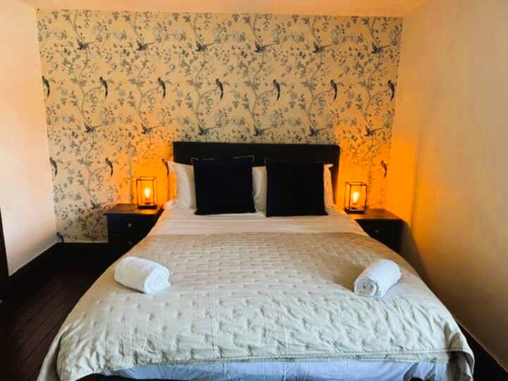 Amplio dormitorio principal con vestidor y zona de maquillaje. Cama tamaño king con ropa de cama y TV alquilada en el hotel. Pisos de madera despojados.