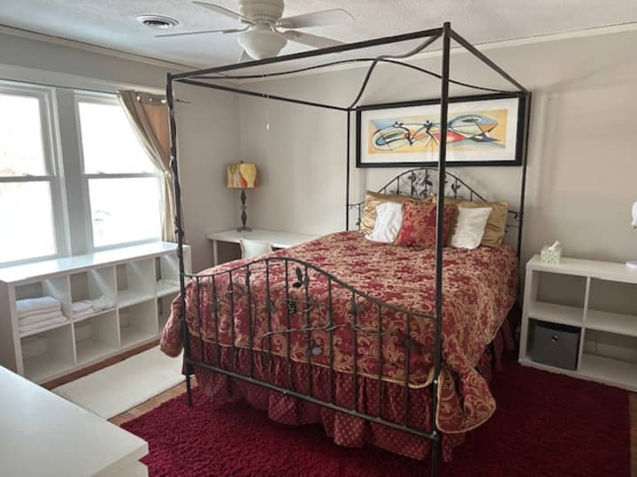 Veľká izba s pohodlnou manželskou posteľou s baldachýnom. Stôl so stoličkou, ďalšou stoličkou na čítanie a poličkami na knihy.