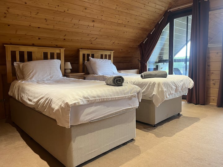 Upstairs bedroom overlooking the front of the house, with two single beds. Balcony has views over the lake. 