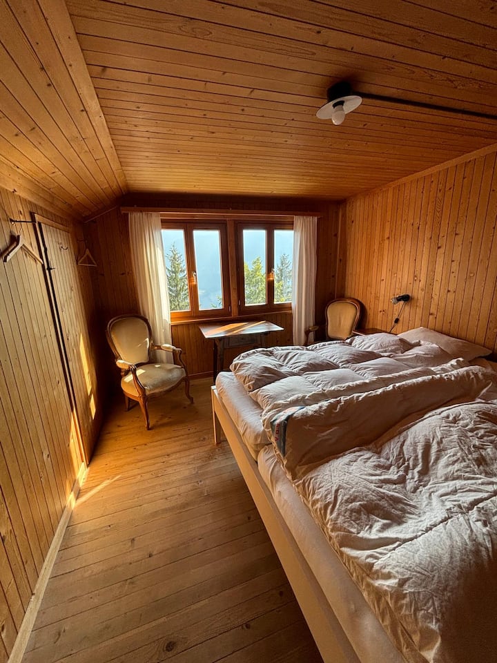 חדר שינה בקומה השנייה עם מיטה זוגית, כורסאות ושולחן.