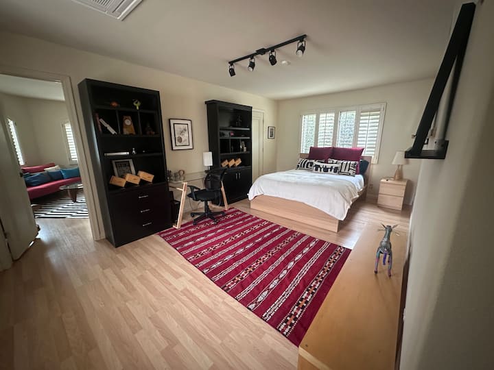 Dhomë e bollshme, e ndriçuar nga dielli, krevat dopio "queen" luksoz me çarçafë të bardhë dhe jastëkë me theks të guximshëm. Përfshin një tavolinë pune elegante prej xhami, karrige ergonomike, rafte të integruara dhe ndenjëse në dritare. Ideale për qëndrime pune nga banesa ose çlodhje. E ndritshme, elegante dhe funksionale