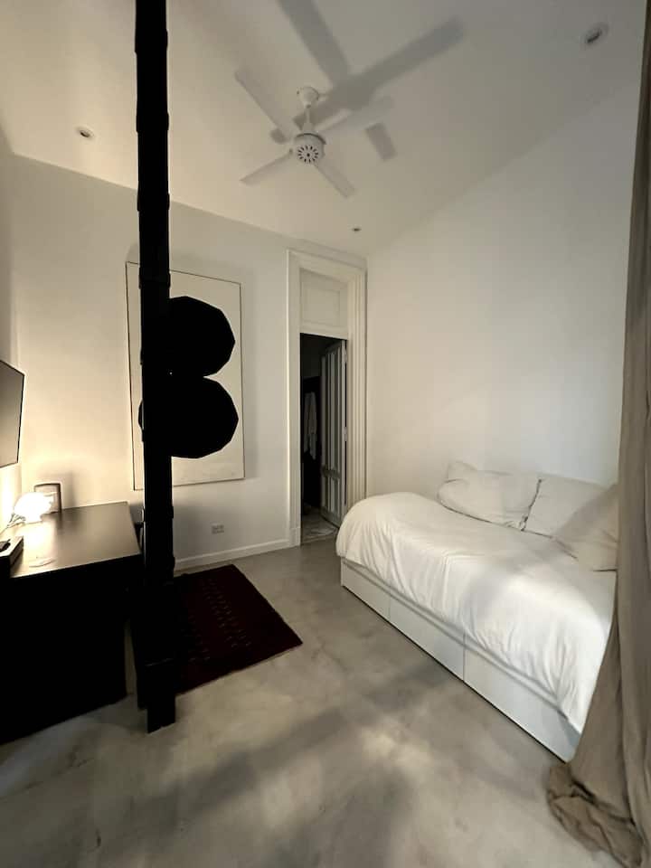 חדר שינה משני עם מיטה של אדם אחד ושולחן עבודה