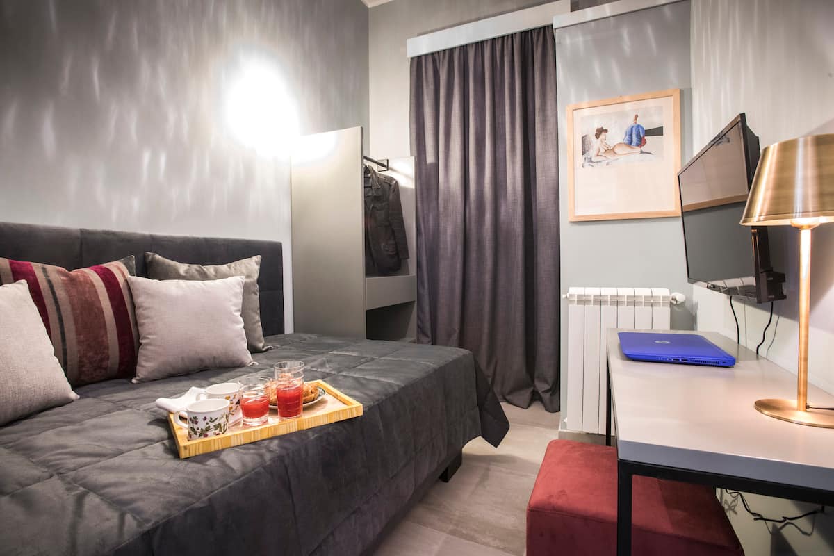 Camera da letto singola con scrivania, lampada in ottone e un'opera incorniciata