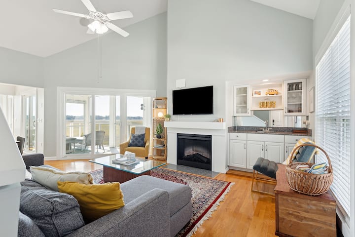 The cozy living room is designed for relaxation with a standard couch and armchair, complemented by a Roku TV for entertainment and electric fireplace. The couch converts into a queen sleeper sofa for additional sleeping arrangements. 