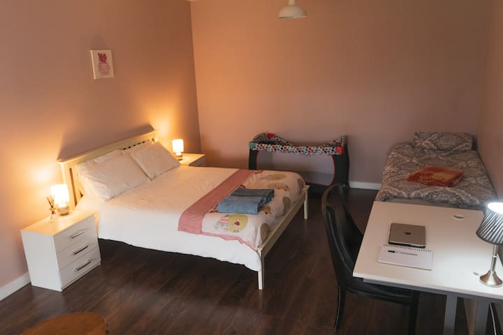 Habitación familiar con cama king, cama individual, cuna, escritorio y sofá. Acceso al comedor al aire libre