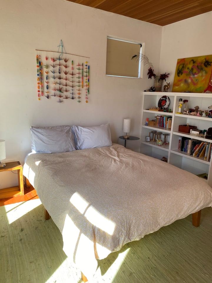 Una cama tamaño queen con luz solar durante el día y persianas que bloquean la luz por la noche.
Un vestidor con amplio espacio para colgar ropa y cajones para guardarla.