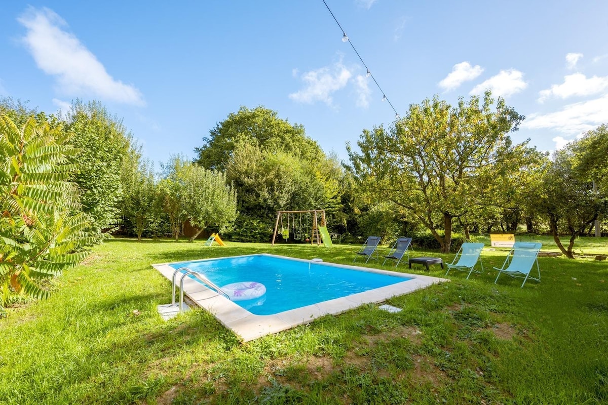 A refreshing outdoor swimming pool is surrounded by a well-maintained grassy area featuring trees and playful greenery. Colorful lounge chairs are arranged around the pool, while a swingset can be seen off to one side, creating a relaxed and inviting space.